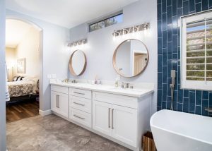Remodeled master bathroom with white double vanity, freestanding tub, and blue vertical tile accent wall