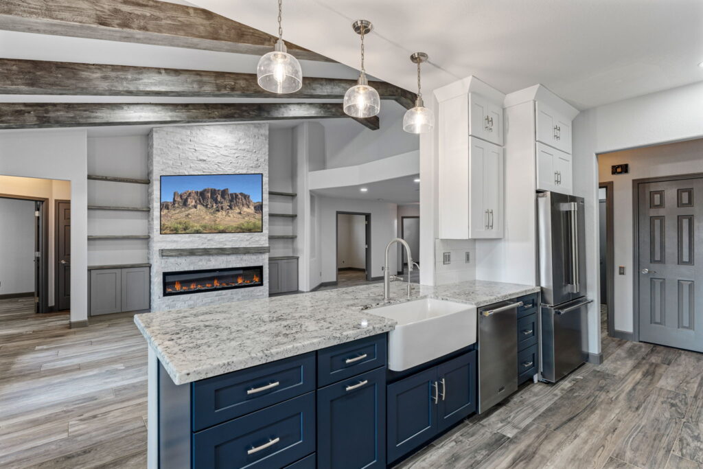 whole-home-remodel-glendale-62nd-15 Wide-angle view of the kitchen and living room, featuring a blue island and a fireplace.